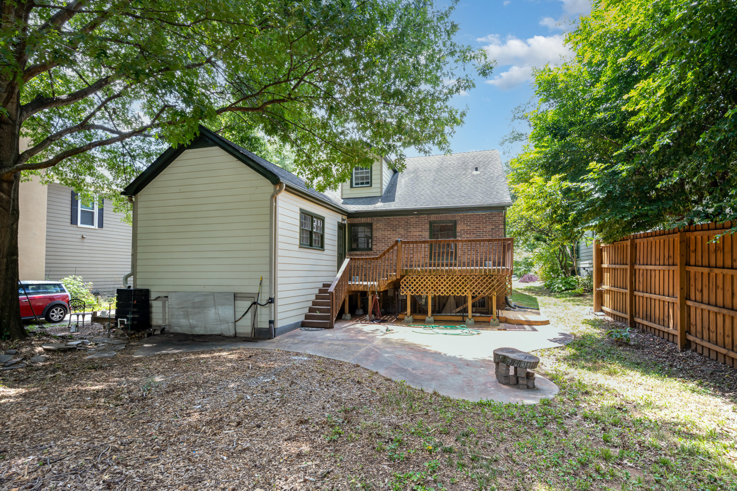 Serene, private backyard with mature shade trees, patio, and deck